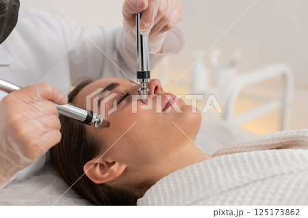 Beautician doctor makes woman micro currents face therapy using electrical impulses in spa salon Beautician doctor makes woman micro currents face therapy using electrical impulses in spa salon 125173862