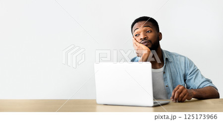 Pensive overworked african american guy dreaming about vacation sitting in office 125173966