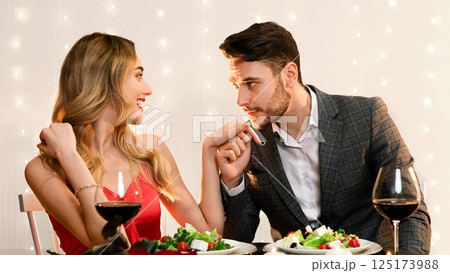 Romantic couple dining in restaurant. Handsome man kissing hand of his pleased girlfriend Romantic couple dining in restaurant. Handsome man kissing hand of his pleased girlfriend 125173988