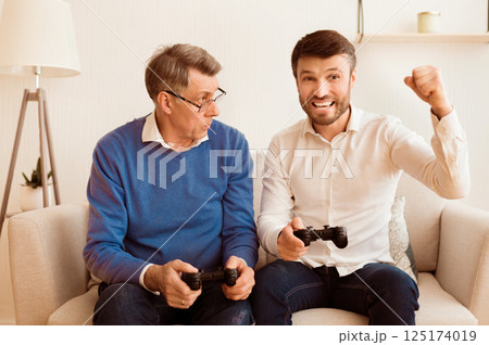 Competition. Upset Senior Man Losing Video Game To His Mature Son Sitting Together On Sofa At Home. 125174019