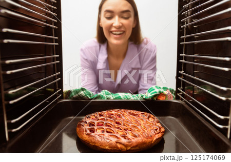 Happy household. Glad housewife taking tasty pie from oven, view from inside Happy household. Glad housewife taking tasty pie from oven, view from inside 125174069