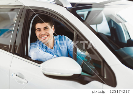 Car Owner. Joyful Guy Smiling To Camera Sitting In New Automobile Driving From Dealership Shop. Selective Focus Car Owner. Joyful Guy Smiling To Camera Sitting In New Automobile Driving From Dealership Shop. Selective Focus 125174217