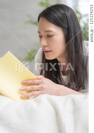 ベッドで読書をするきれいな女性｜勉強｜趣味｜健康的な暮らしイメージ｜ウェルビー女子｜ウェルビーイング 125174253