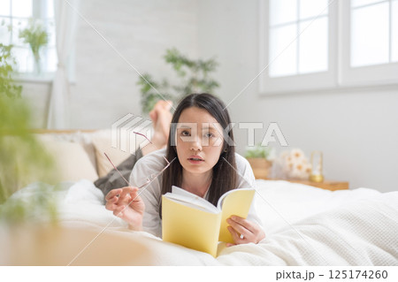 ベッドで読書をするきれいな女性｜勉強｜趣味｜健康的な暮らしイメージ｜ウェルビー女子｜ウェルビーイング 125174260