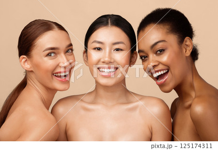 Three Joyful Models Girls Posing Smiling To Camera Standing Shirtless On Gray Background. Studio Shot. Natural Beauty Concept Three Joyful Models Girls Posing Smiling To Camera Standing Shirtless On Gray Background. Studio Shot. Natural Beauty Concept 125174311