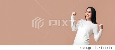 Yes, I did it. Euphoric brunette girl celebrating success with raised fists, rejoicing victory or personal achievement over yellow background, panorama 125174314