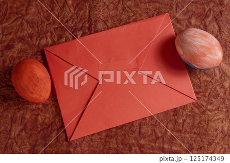 Red envelope with decorative painted eggs on a rustic background. Red envelope with decorative painted eggs on a rustic background. 125174349