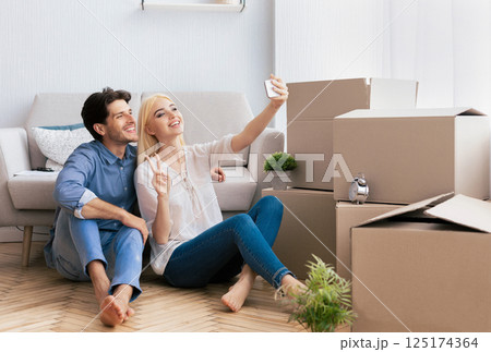 Happy House Owners. Couple Taking Selfie With Smartphone Gesturing Victory Sign After Moving Into New Home. Copy Space 125174364