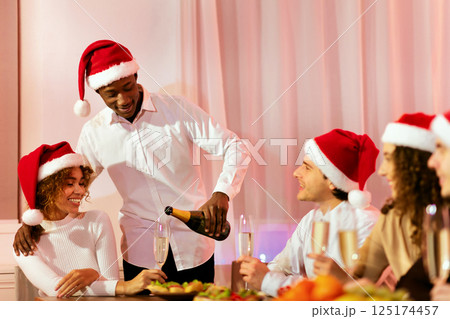 Xmas Corporate Party. Black Man Serving Champagne Filling Glasses Celebrating Christmas With Diverse Friends At Home 125174457