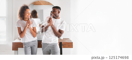 A young African American couple stands in a stylish, bright room, smiling and engaging playfully with each other, surrounded by minimal decor and natural light. A young African American couple stands in a stylish, bright room, smiling and engaging playfully with each other, surrounded by minimal decor and natural light. 125174698