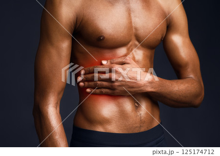 Left Side Pain. Handsome black bodybuilder with red dot suffering from gastritis, sore zone, shirtless torso 125174712