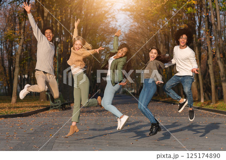 Carefree international students jumping in the air, having fun in park Carefree international students jumping in the air, having fun in park 125174890