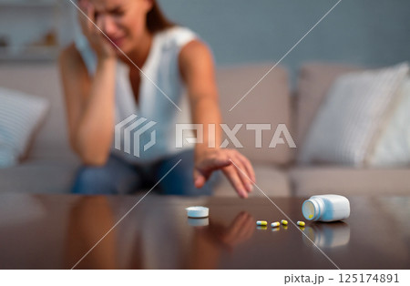 Depression Concept. Desperate Woman Reaching For Antidepressant Or Sleeping Pills Sitting On Sofa At Home. Selective Focus Depression Concept. Desperate Woman Reaching For Antidepressant Or Sleeping Pills Sitting On Sofa At Home. Selective Focus 125174891