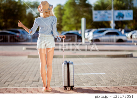 Catch Taxi. Young woman wearing summer hat, standing near airport and trying to stop car, full length, back view Catch Taxi. Young woman wearing summer hat, standing near airport and trying to stop car, full length, back view 125175051