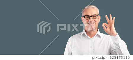 Everything is OK. Happy mature man in glasses showing approval gesture and smiling, blue studio wall, copyspace Everything is OK. Happy mature man in glasses showing approval gesture and smiling, blue studio wall, copyspace 125175110