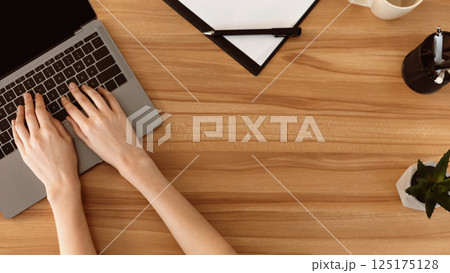 Education. Top view female hands typing on a laptop keyboard with isolated screen on wood desk with office supplies 125175128