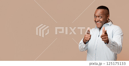 Gotcha. Middle aged afican man pointing at camera, orange studio background 125175133