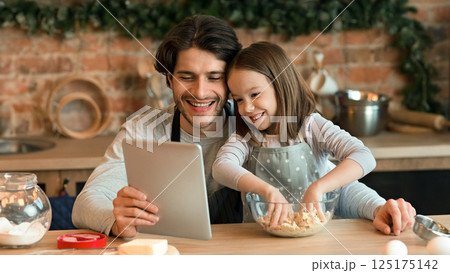 Cute Little Girl And Her Dad Checking Recipe On Digital Tablet While Cooking Pastry In Kitchen Together, Little Girl Kneading Dough, Closeup Cute Little Girl And Her Dad Checking Recipe On Digital Tablet While Cooking Pastry In Kitchen Together, Little Girl Kneading Dough, Closeup 125175142