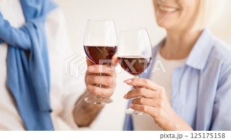 Mature couple clinking glasses of red wine, celebrating anniversary at home 125175158