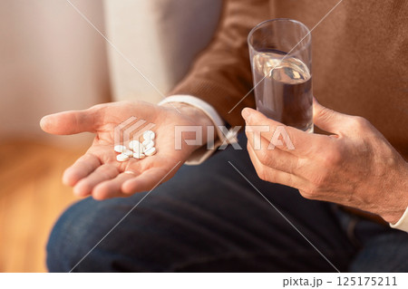 Unrecognizable Senior Gentleman Holding Pills And Water Sitting On Sofa At Home. Cropped, Selective Focus 125175211
