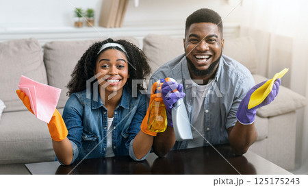 Stay At Home Concept. Loving Black Couple Cleaning Flat, Wiping Dust From Table In Living Room, Spending Quarantine Time Together And Smiling 125175243