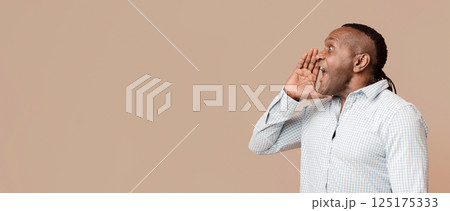 Hello. Mature african man shouting aside at free space, orange panorama background 125175333