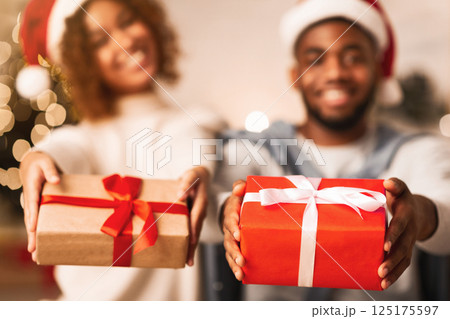 Merry Christmas. African-american couple stretching gift boxes to camera and smiling 125175597