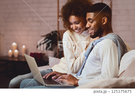 Young married couple using laptop at cozy winter evening, resting at home, free space Young married couple using laptop at cozy winter evening, resting at home, free space 125175675