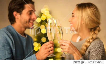 Happy couple with glasses of champagne celebrating Christmas at home, looking at each other Happy couple with glasses of champagne celebrating Christmas at home, looking at each other 125175889