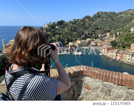 Photographer, blogger shoots panorama of old traditional village in Italy. Mediterranean Sea, Ligurian coast. Nature of Portofino. View from mountain. 125175905