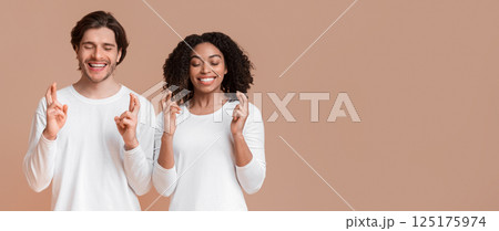 Making A Wish. Young interracial couple crossing fingers with closed eyes, posing together over yellow studio background Making A Wish. Young interracial couple crossing fingers with closed eyes, posing together over yellow studio background 125175974