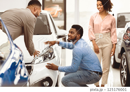 Car Rental. Afro Couple Choosing And Checking Auto With Manager In Automobile Rent Service Center. Selective Focus 125176001
