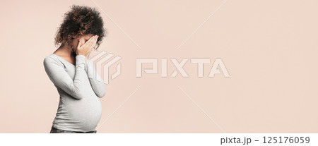 Hormones during pregnancy. Depressed expectant lady closing her face and crying, grey studio background 125176059