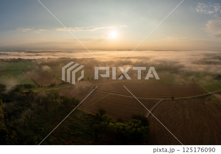 Drone aerial view at golden hour with foggy rolling agricultural fields Drone aerial view at golden hour with foggy rolling agricultural fields 125176090