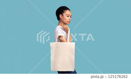 No Plastic. Black Girl Holding Blank White Eco Bag Posing Over Turquoise Studio Background. Panorama, Empty Space No Plastic. Black Girl Holding Blank White Eco Bag Posing Over Turquoise Studio Background. Panorama, Empty Space 125176262