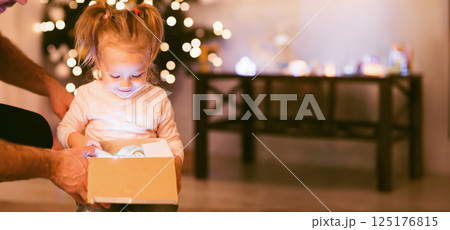 Christmas magic. Amazed little girl opening glowing Xmas gift Christmas magic. Amazed little girl opening glowing Xmas gift 125176815
