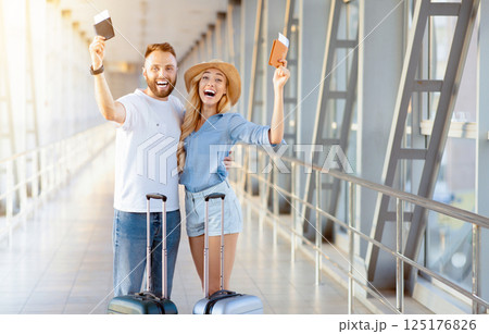 Tourism and vacation concept. Happy couple with passports and air tickets at airport terminal, free space 125176826