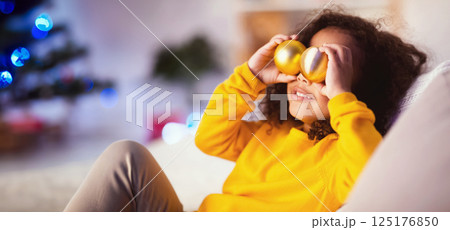 Christmas vision. Happy african american child making eyeglasses with Xmas tree decoration balls, free space 125176850