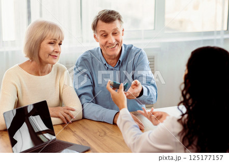 Asthma Treatment. Female doctor giving blue inhaler to senior patient who is sitting with his mature wife, copyspace 125177157