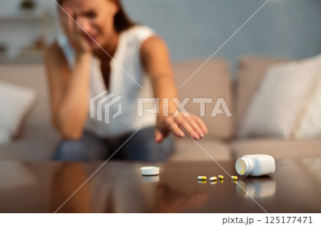 Depression. Suicidal Girl Reaching After Antidepressant Or Sleeping Pills Sitting On Couch Indoor. Selective Focus, Shallow Depth 125177471