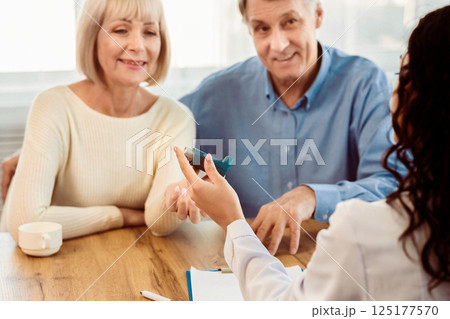 Asthma Attacks. Unrecognizable nurse giving blue inhaler to smiling mature couple, selective focus Asthma Attacks. Unrecognizable nurse giving blue inhaler to smiling mature couple, selective focus 125177570