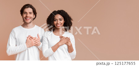Grateful Multiracial Couple Expressing Gratitude With Hands On Chest, Posing Together Over Yellow Background With Free Space 125177655