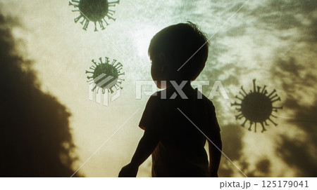 A young child stands in silhouette, looking up at ominous virus illustrations against a glowing background. This moment captures the child's curiosity and the serious nature of health concerns today. 125179041