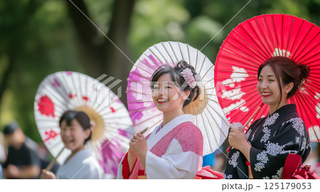 Japanese women in colorful Yukata celebrate during a summer festival with traditional umbrellas in a park 125179053