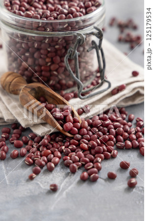 Glass jar full of dried azuki beans with a wooden scoop closeup. Vegetarian protein source Glass jar full of dried azuki beans with a wooden scoop closeup. Vegetarian protein source 125179534