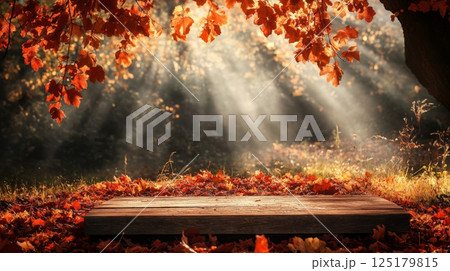 Golden rays of sunlight illuminate a tranquil spot in the woods where a wooden platform rests on a carpet of fallen autumn leaves, creating a peaceful atmosphere in nature's beauty. 125179815