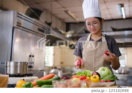 Culinary student standing confidently in training kitchen with fresh ingredients ready for cooking practice Culinary student standing confidently in training kitchen with fresh ingredients ready for cooking practice 125182698