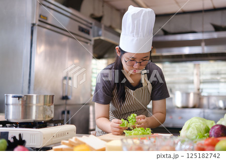 Focused chef carefully a gourmet sandwich in a professional kitchen with fresh ingredients in view 125182742