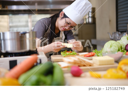 Focused chef carefully a gourmet sandwich in a professional kitchen with fresh ingredients in view Focused chef carefully a gourmet sandwich in a professional kitchen with fresh ingredients in view 125182749