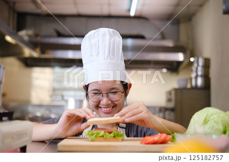 Focused chef carefully a gourmet sandwich in a professional kitchen with fresh ingredients in view Focused chef carefully a gourmet sandwich in a professional kitchen with fresh ingredients in view 125182757